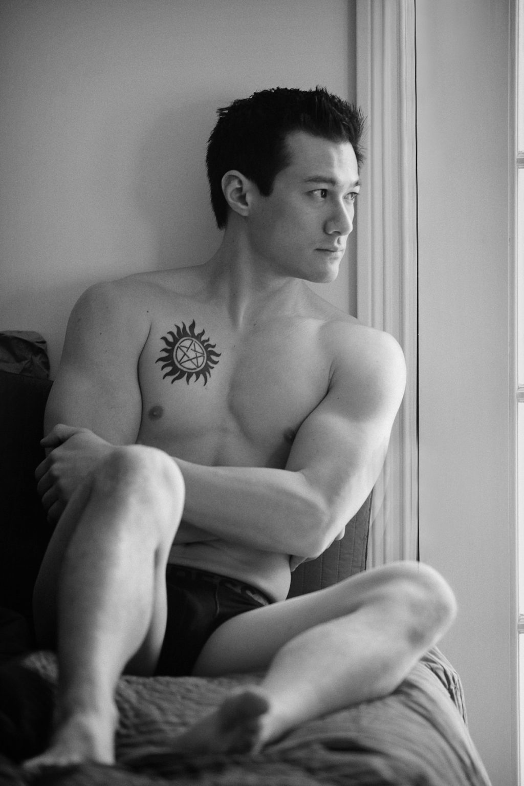a man sits on a bed in his boxer briefs at a chicago boudoir studio