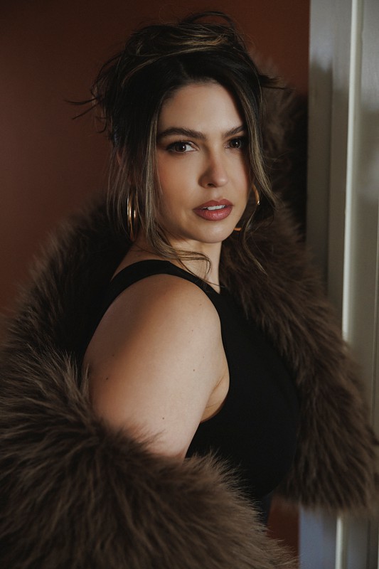 a woman looks over her shoulder wearing a fur jacket and black bodysuit during her photoshoot at Revealed Studios chicago boudoir photo studio