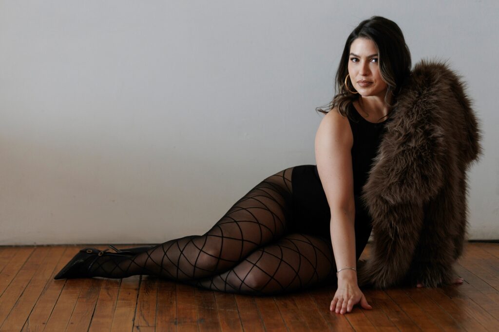 woman wearing fur coat and fishnets posing at a boudoir studio in chicago