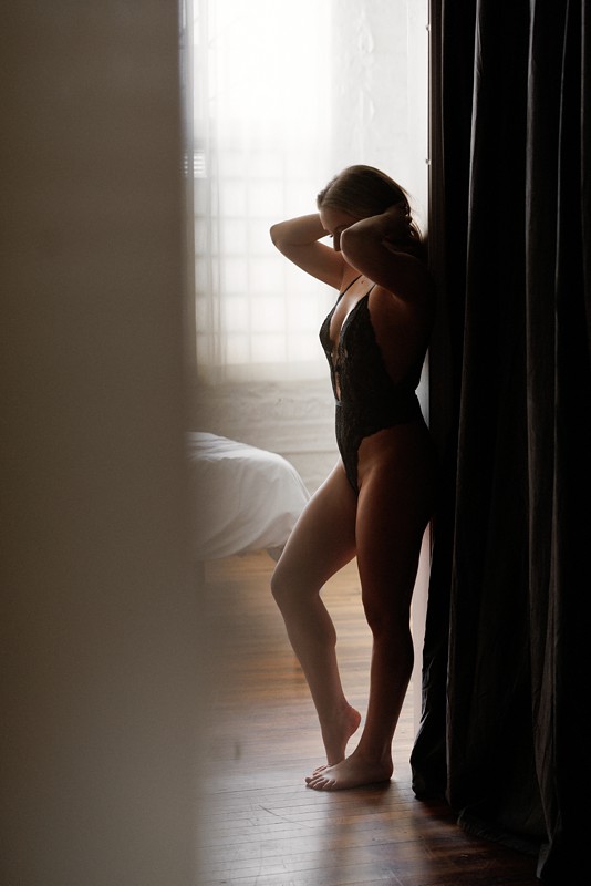 woman silhouetted against a doorway wearing a black bodysuit at Revealed Studios chicago boudoir photo studio